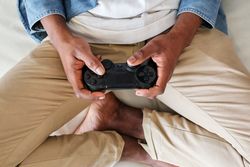 Crop unrecognizable Black man with game pad resting on couch