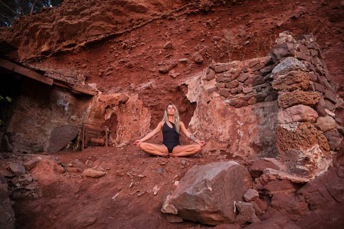 Fit female meditating in rocky mountains