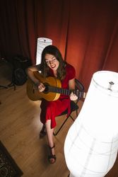 Woman singing and playing guitar on stage in lamplight