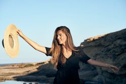 Cheerful woman holding hat in air