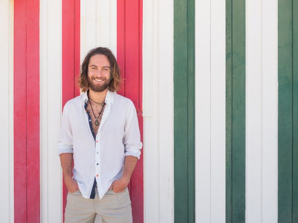 Cheerful guy standing near striped wall