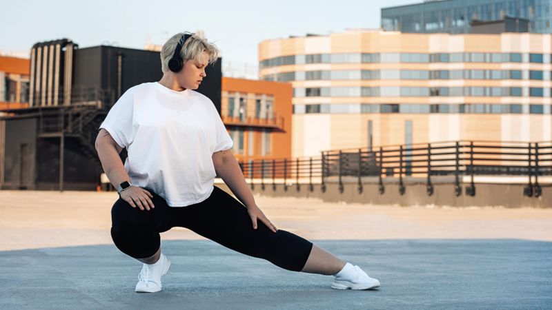 Curvy woman warming up for her workout on a rooftop