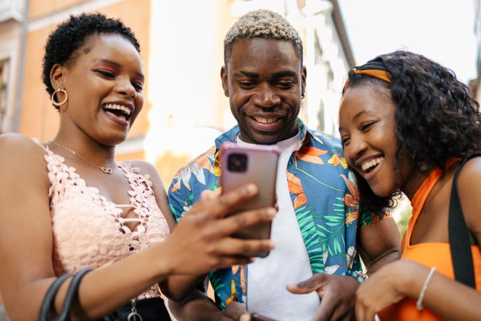 Three friends using smartphone in the street