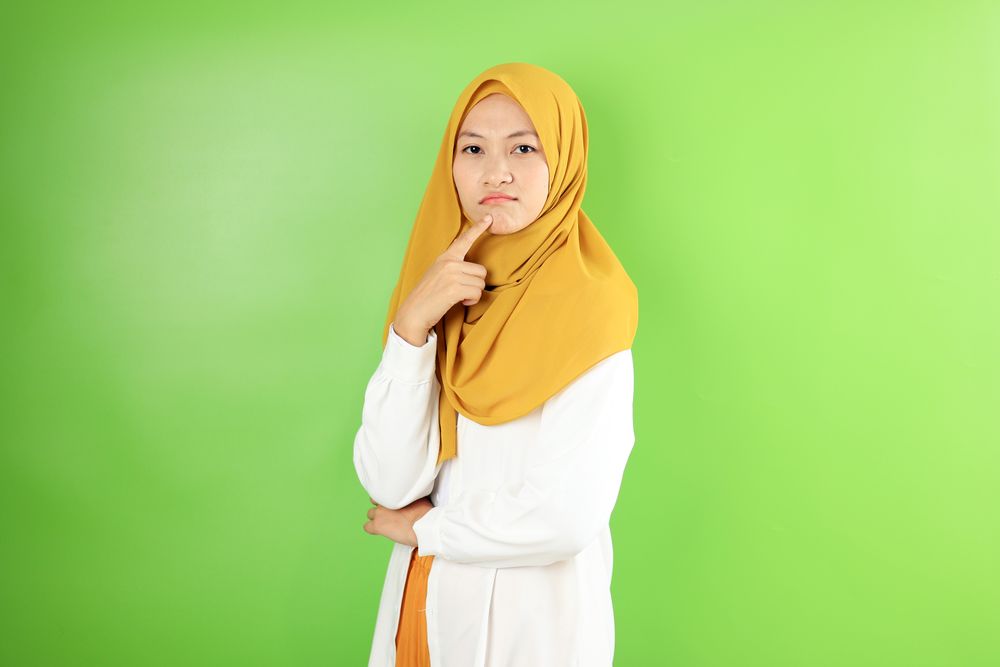Asian Young Hijab Woman Pouting and Thinking Looking at Camera