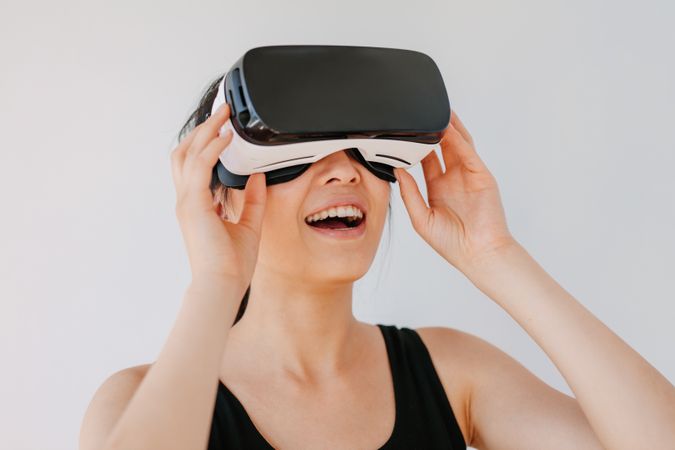 Close up of happy young woman using the VR goggles against grey background