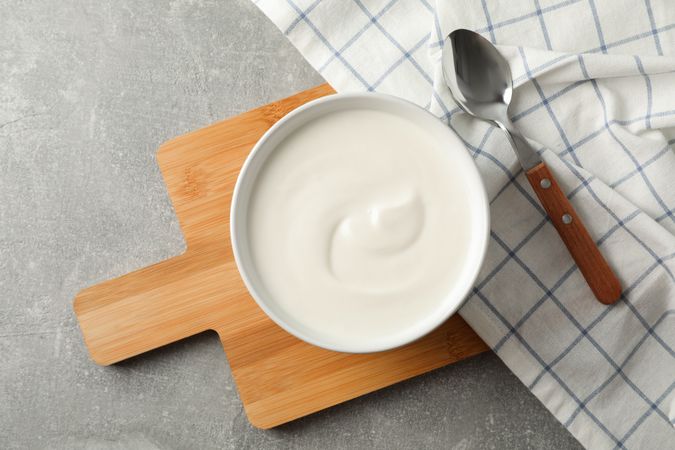 Composition with yogurt in bowl on grey background