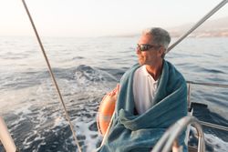 Smiling man in towel on yacht on water