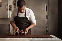 Man in apron slicing cake in professional kitchen 42NZq4