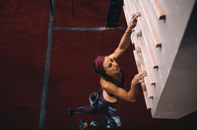 Fit woman practicing wall climbing skills on campus board