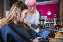 Hairdresser and client choosing hair color from digital tablet beWmq5