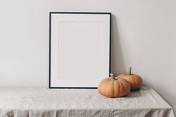 Vertical picture frame mockup with pale orange pumpkins on linen table cloth