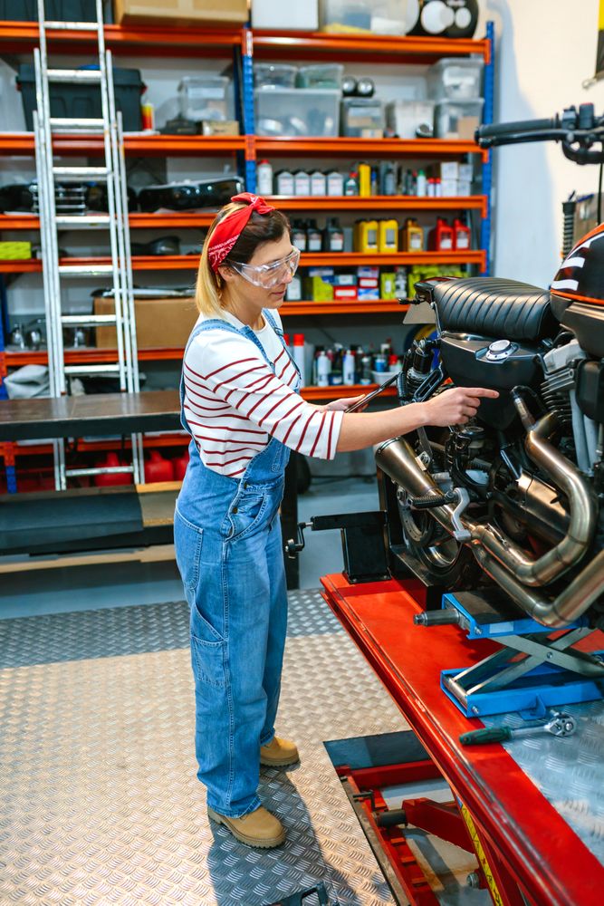 Mechanic with security glasses and digital tablet checking motorbike failure on workshop