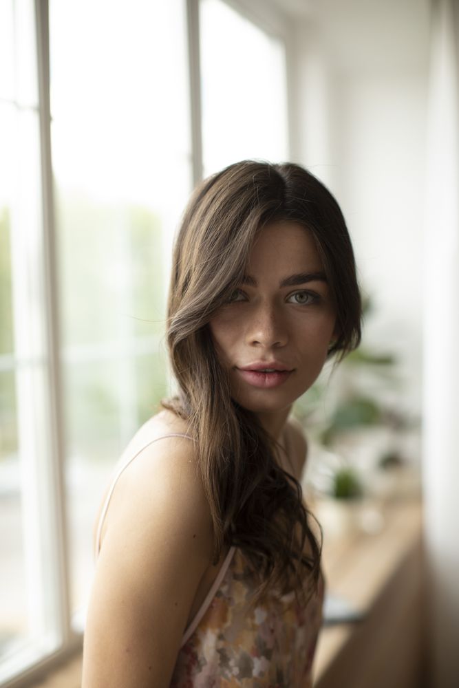 Woman with long brown hair and light eyes looking at camera