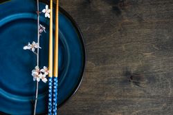 Top view of table setting with chop sticks on ceramic navy plate and delicate cherry blossom branch