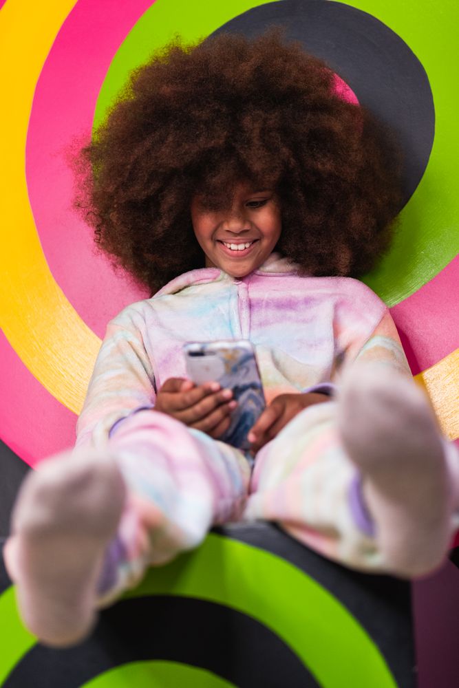 Smiling Black girl using mobile phone in studio