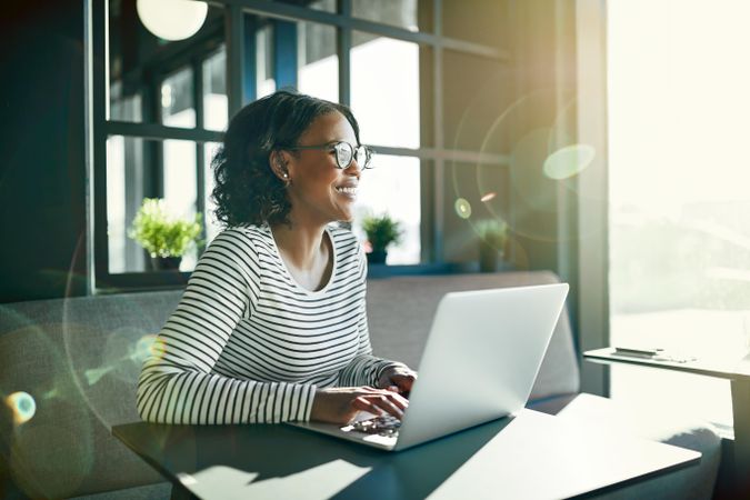 Laughing woman working at laptop in cafe