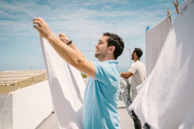Multiracial men hanging clothes in bright day