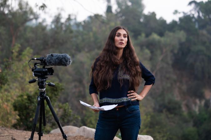 Female director standing next to camera with hand on hip
