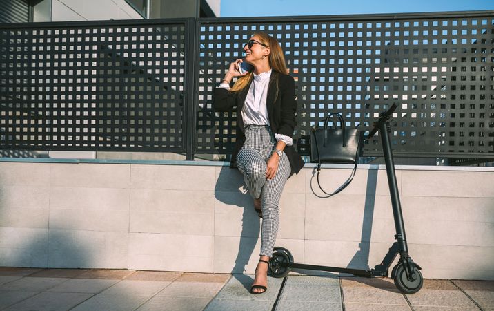 Businesswoman with mobile and her scooter next