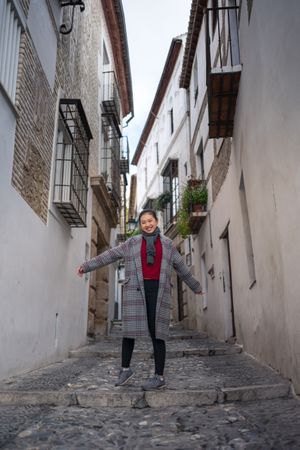 Joyful female tourist in casual wear amid city street