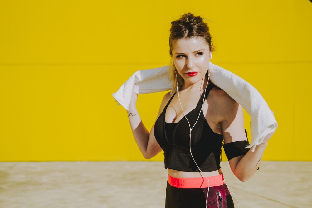Woman cleaning with sweat towel on yellow background