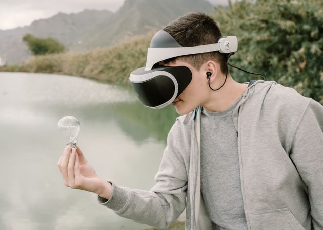 Young teenager with virtual reality glasses holding a light bulb