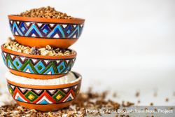 Side view of colorful bowls full of different grains bGRvJ2
