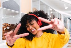Carefree Black woman in headphones showing victory sign