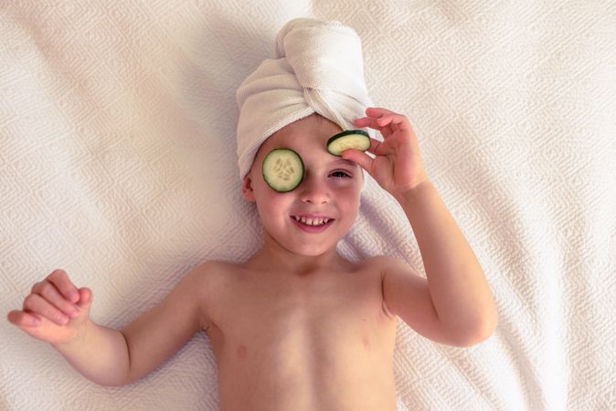 Cheerful boy with cucumber slices on eyes