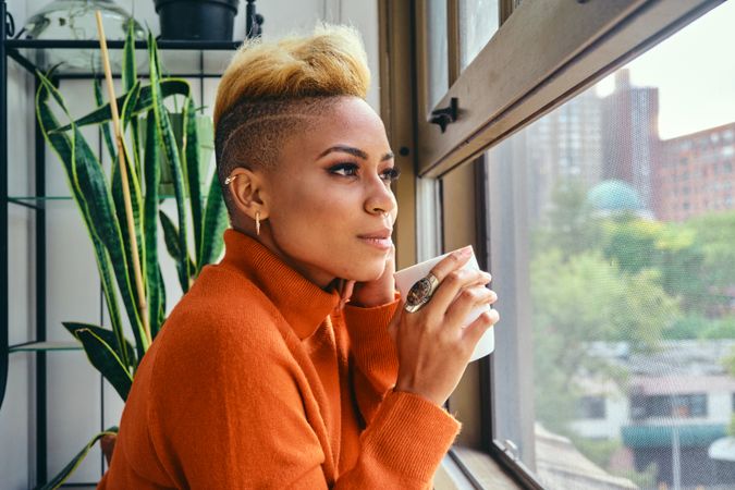 Black woman thinking deeply over a cup of coffee at the window