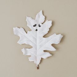 Flat lay Halloween background made with autumn leaf painted as ghosts