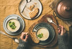 Woman holding spoon, with toast and celery soup