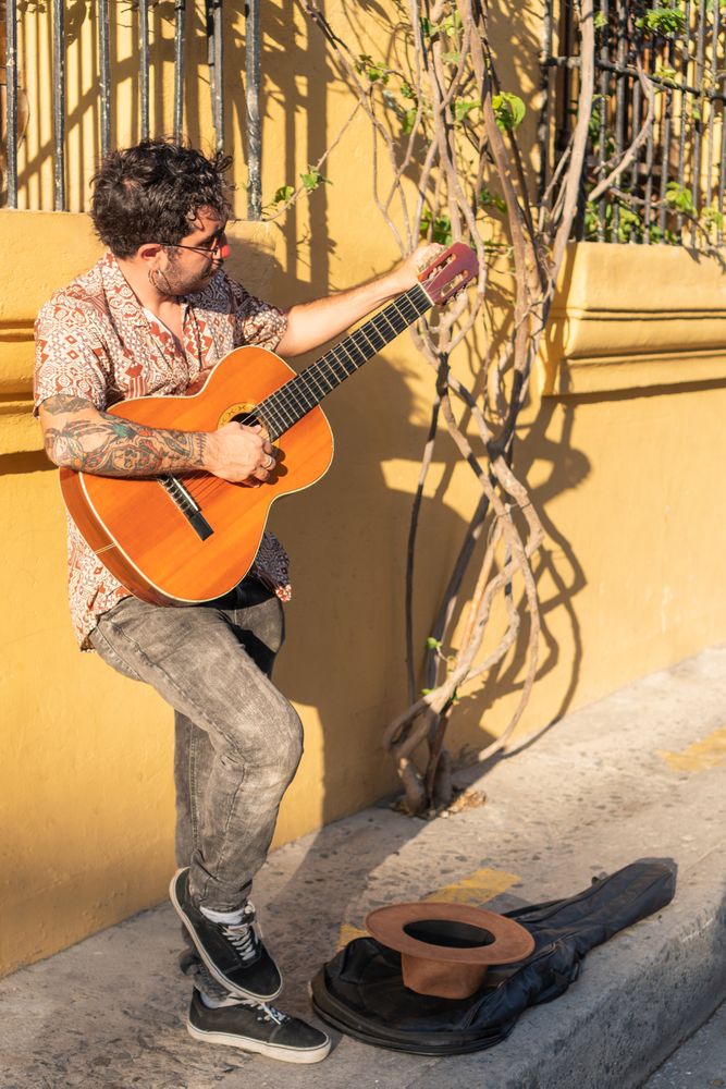 Young man playing guitar standing on the street