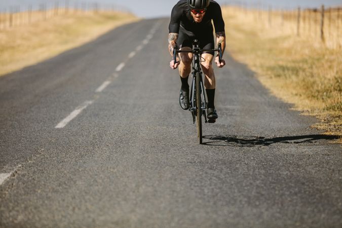 Athlete riding bicycle on empty road