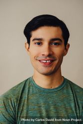 Portrait of smiling Hispanic male in neutral room wearing green t-shirt bEZJ10