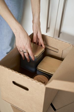 Anonymous woman holding containers out of box