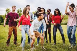 Cheerful happy young people having fun dancing together in park