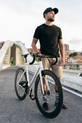 Cheerful man with bicycle standing on footbridge