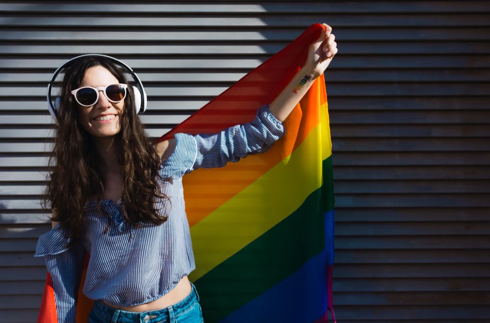 White woman posing happily with the LGBT flag