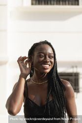 A young Black woman smiles happily as she fixes her hair with her hand 4mWWLN