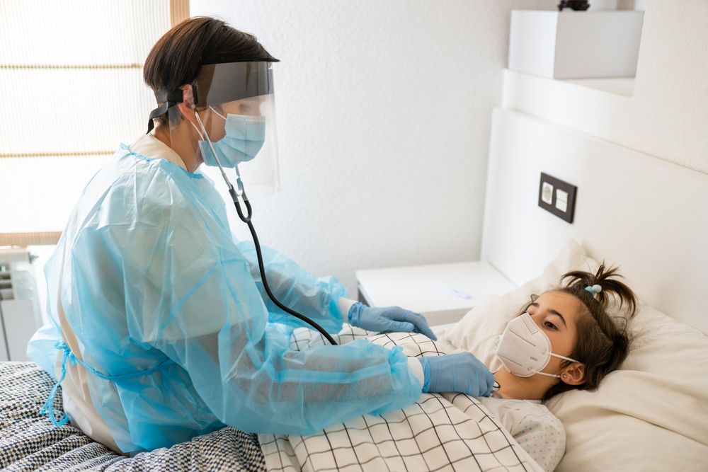 Nurse in full PPE checking on sick child