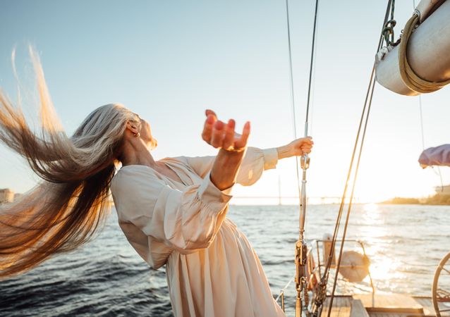 Mature woman with long gray hair flowing in the wind on a boat