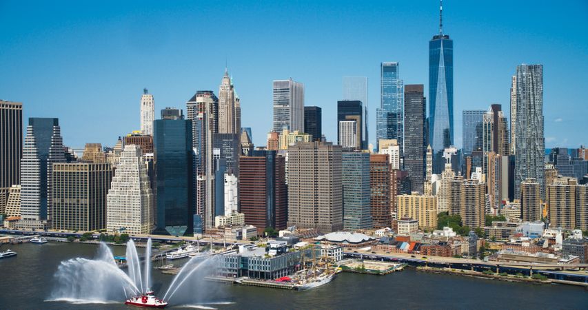 Aerial Helicopter Shot Over Midtown Manhattan Skyscrapers Cityscape with Reflective Glass Windows. Beautiful Blue Sky on a Sunny Day Reflecting on Buildings
