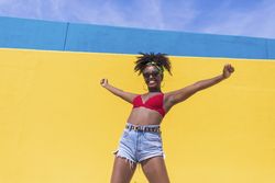Confident Black woman smiling with arms raised