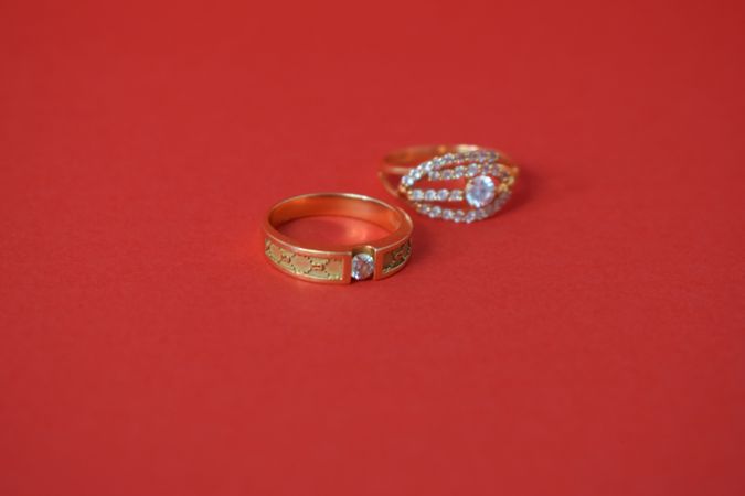 Two diamond rings on red table with copy space