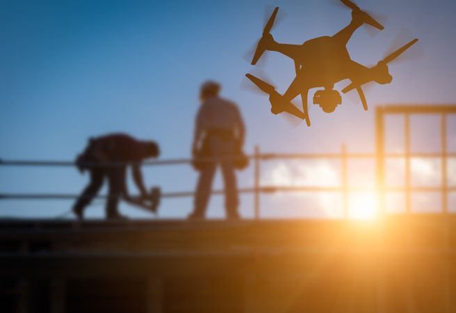 Unmanned Aircraft System (UAV) Quadcopter Drone In The Air Over Building Under Construction.