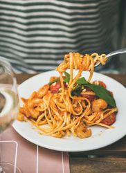 Person in striped shirt eating pasta with fork