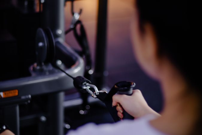 Engaged female athlete pulling cable weight machine at gym workout