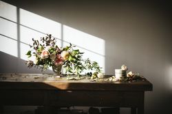 plate with cake decorated flower on table with bouquet of blooms in vase