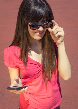 Young woman with phone looking over her sunglasses